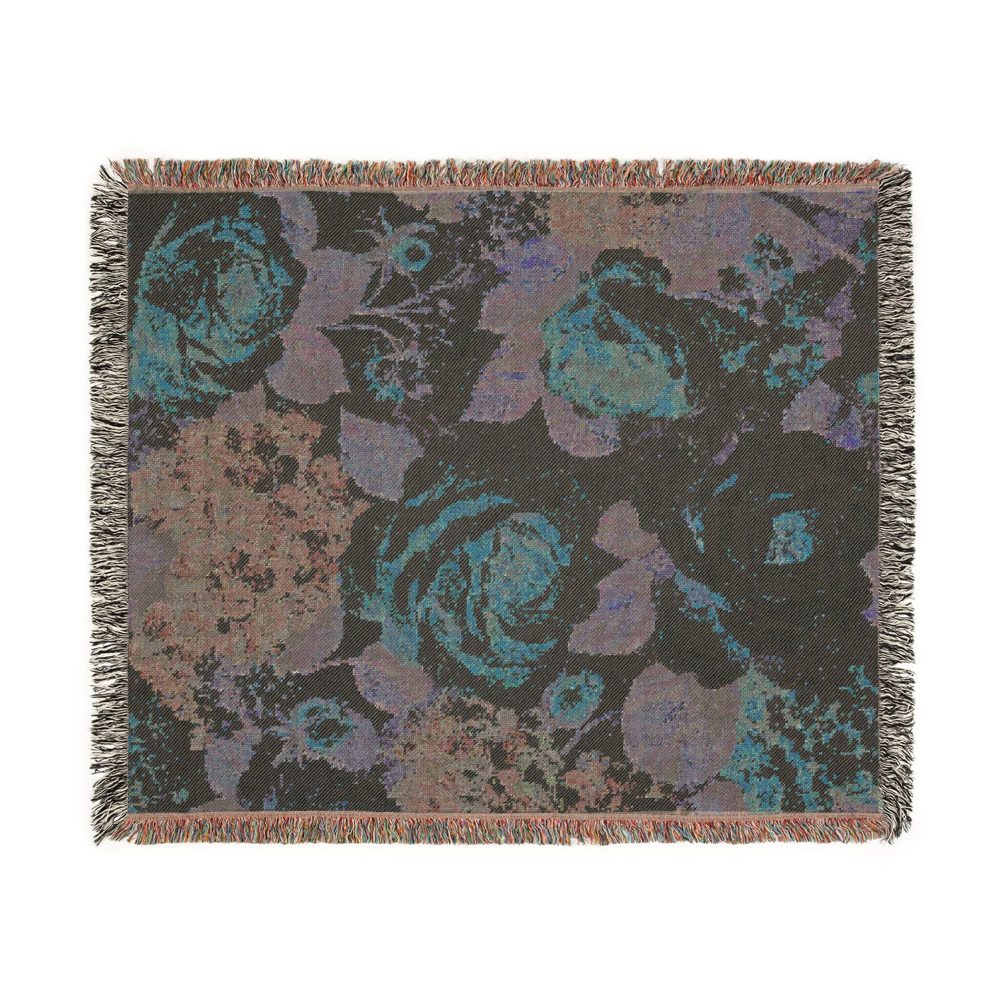 A rectangular woven throw blanket with fringed edges, featuring an abstract floral pattern in teal, purple, and brown tones on a dark charcoal background.