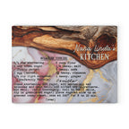 A square decorative sign or print featuring a marble-style background with a wooden spoon, the text 'Nana Linda's KITCHEN,' and a recipe for vanilla molasses cookies printed in black script and block lettering.