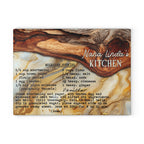 A square decorative recipe card or print titled 'Nana Linda's Kitchen' showing a vanilla molasses cookie recipe in black text over a marbled wood-and-gold background with a wooden spoon illustration.