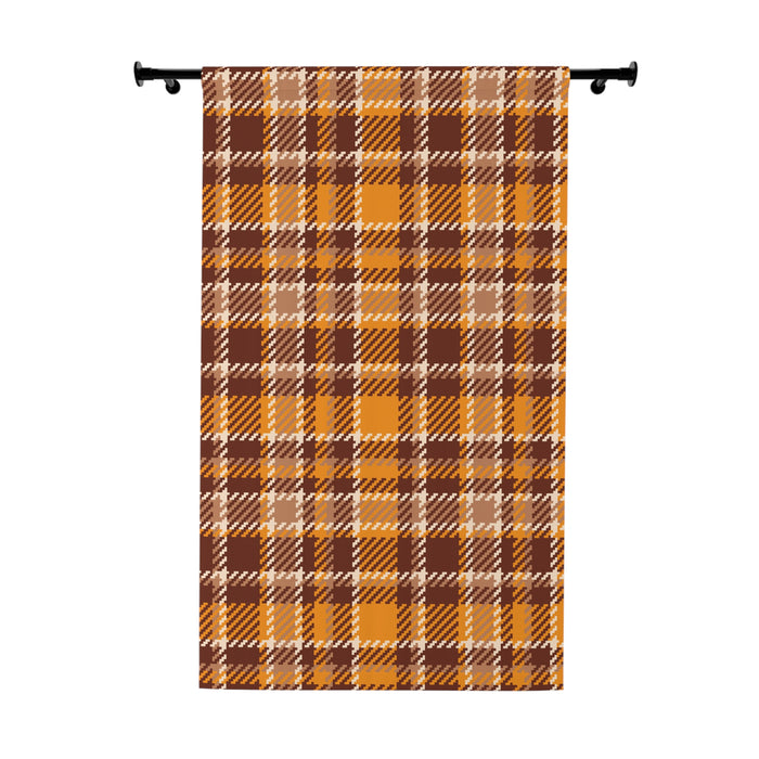 A vertical fabric panel or curtain featuring a classic autumn plaid pattern in orange, brown, beige, and white, hanging from a black rod against a plain white background.
