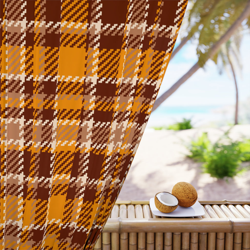 A close-up of a brown, orange, and beige plaid fabric panel draped over a bamboo table, with a blurred tropical beach scene in the background featuring palm trees and a coconut on a small white plate.