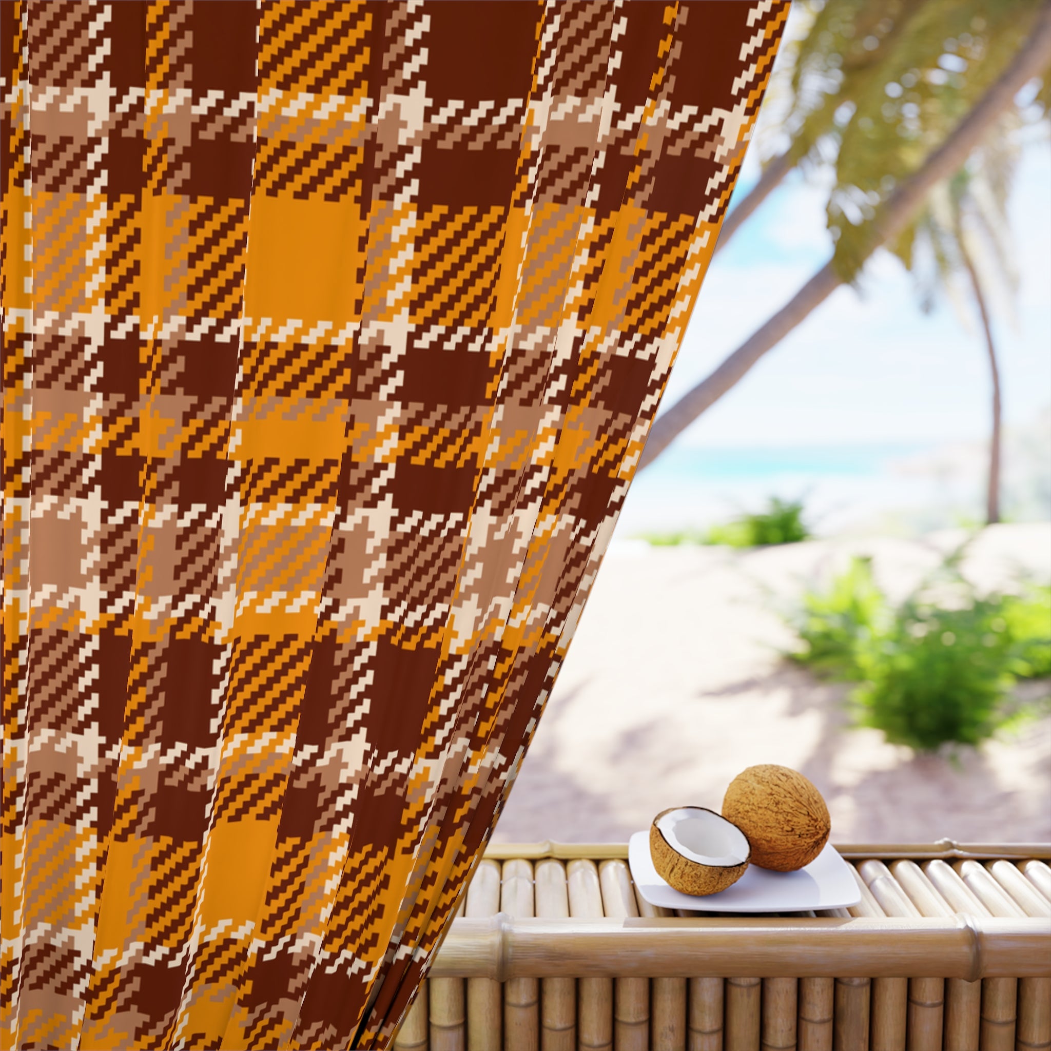 A close-up of a brown, orange, and beige plaid fabric panel draped over a bamboo table, with a blurred tropical beach scene in the background featuring palm trees and a coconut on a small white plate.