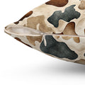 Close-up of a square throw pillow with a camouflage pattern in beige, brown, and dark gray, featuring a white zipper along the edge.