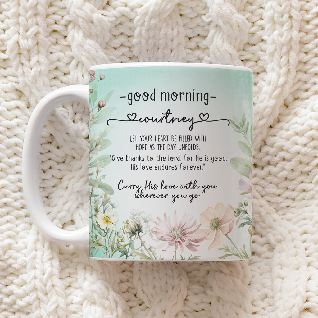 A white ceramic mug with a pastel floral design and a personalized quote for 'courtney', placed on a textured cream knit blanket.
