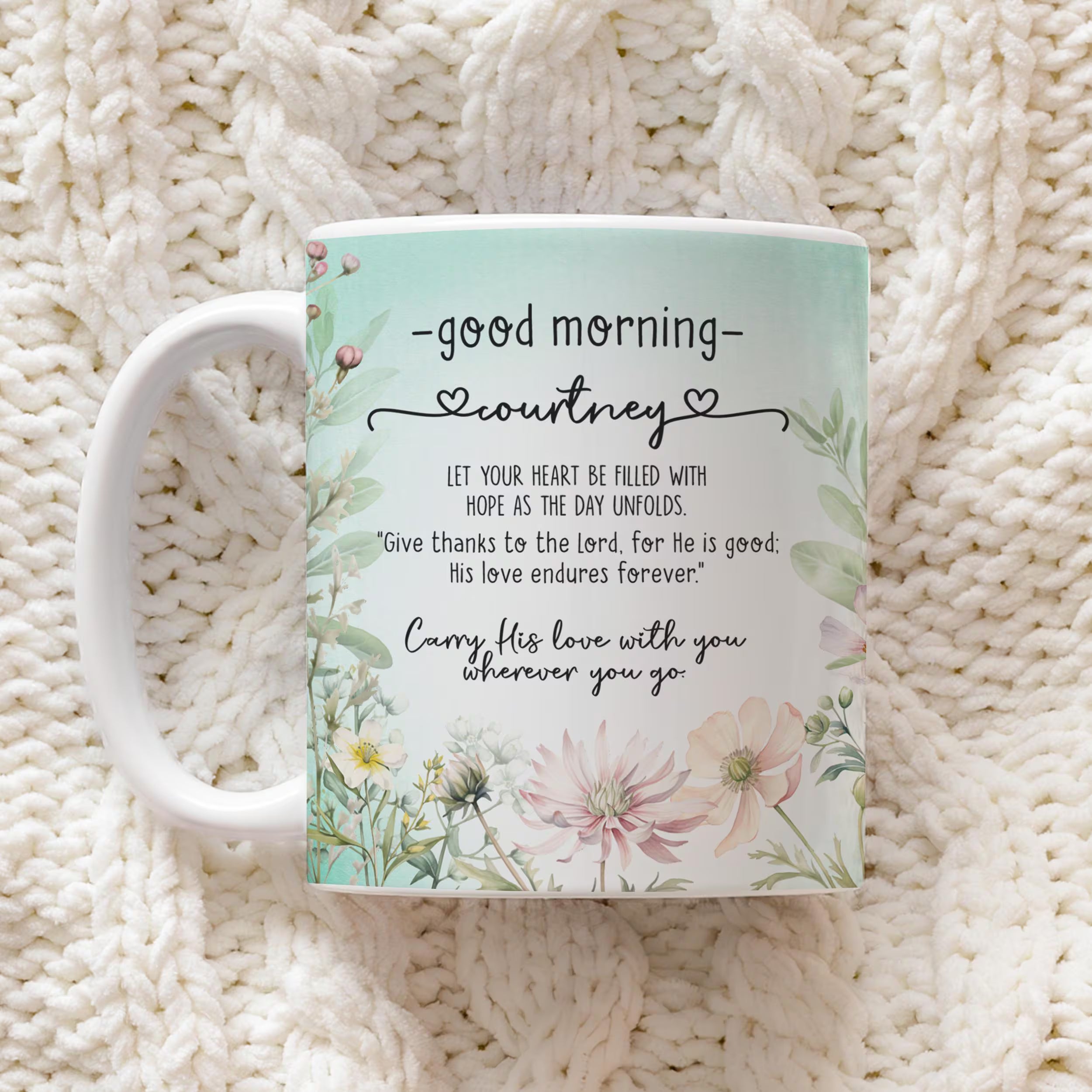 A white ceramic mug with a pastel floral design and a personalized quote for 'courtney', placed on a textured cream knit blanket.