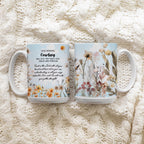 Two ceramic mugs with floral and inspirational designs, placed side by side on a chunky cream knit blanket.
